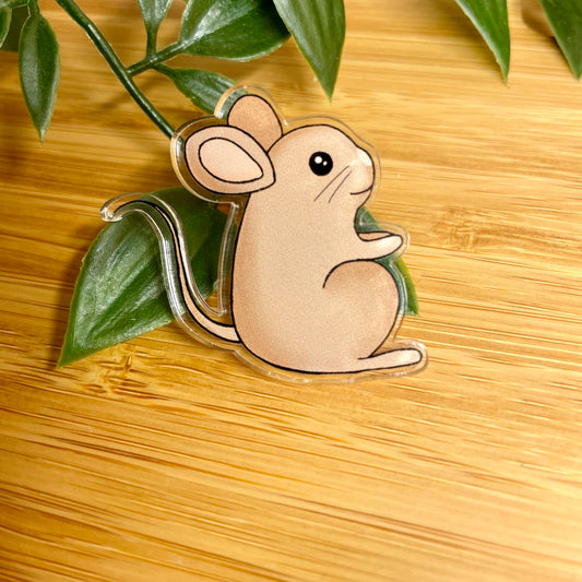 Wooden mouse pin badge on a wooden surface with leaves